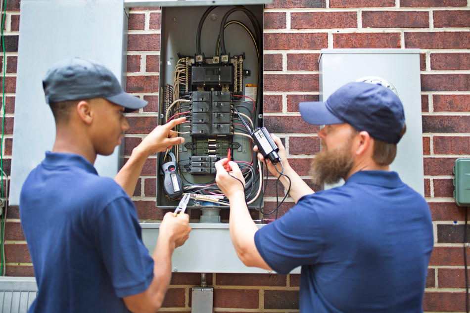 Two men electricians working on a residential breaker box.